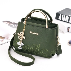 Forest green leather handbag with rose embroidery and gold handle in lifestyle setting
