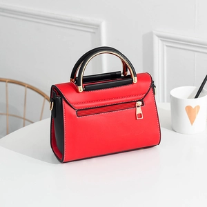 Sac à bandoulière moderne en cuir rouge et noir avec poignée dorée sur table blanche
