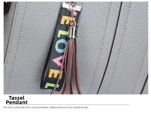 Détail du cuir gris grainé avec un pendentif pompon LOVE coloré sur le sac