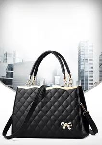 Detail der schwarzen gesteppten PU-Handtasche mit goldener Schleifenschnalle und festem Griff