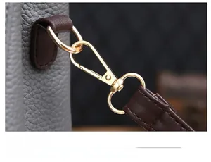 Détail de la boucle en métal doré et de la bandoulière en cuir marron sur sac gris