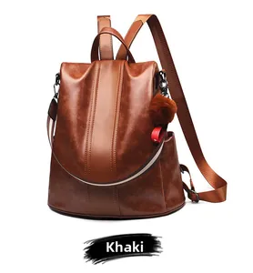 Detail view of khaki faux leather backpack with plush ball charm and side pocket