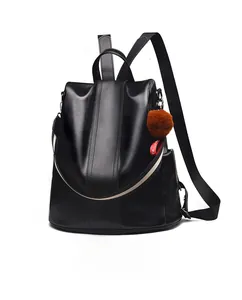 Close-up of black faux leather backpack with brown plush charm and stitching detail