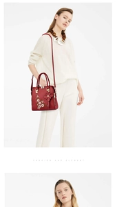Close-up of red handbag with white daisy embroidery and 3D leather flower charm details