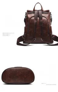 Detail view of the brown leather backpack showing the back zipper and oval bottom base