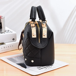 Quilted black leather handbag with gold hardware and rhinestone trim on a wooden table