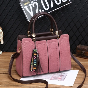 Sac à main rose en cuir grainé avec poignées marron foncé et breloque à pampille