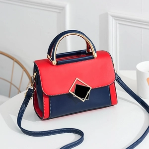 Fashionable color-block PU crossbody bag with gold metal handle on a white desk