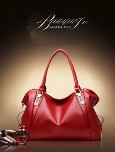 Detail of red lychee grain leather handbag with gold metal buckles and soft handle