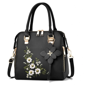 Black faux leather tote bag with elegant floral embroidery and golden hardware