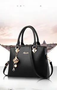 Détail du sac à main noir en similicuir avec logo en métal, breloque fleur et poignées