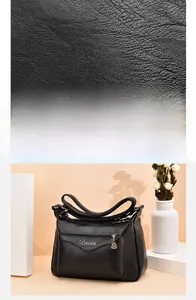 Detail of black lychee grain PU leather shoulder bag with metallic logo and zippers