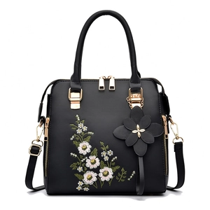 Elegant black embroidered handbag with floral patterns and a detachable flower charm