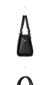 Detail view of black faux leather handbag showing gold hardware and textured finish