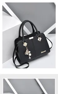 Detail of black lychee grain leather handbag with pearl flower charm and gold hardware