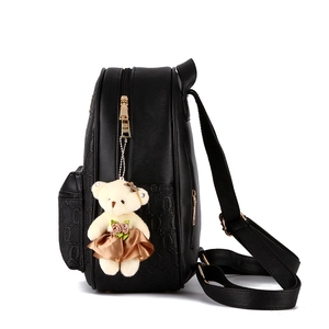 Minimalist black embossed backpack for women with teddy bear charm in a side profile view