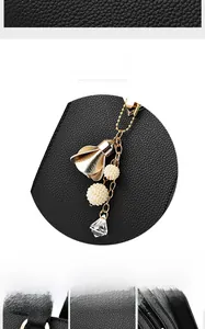 Close-up of black lychee texture leather bag with elegant flower and pearl charm pendant