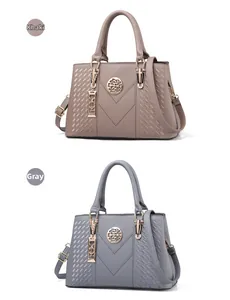 Detail of khaki and grey embroidered handbags with V-shaped stitching and gold hardware