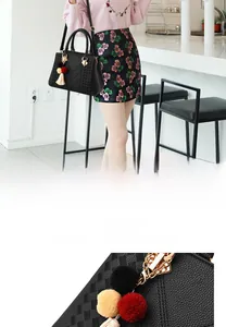 Detailansicht der schwarzen Lederhandtasche mit dreifarbigem Pelzball und Quastenanhänger