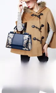 Detail of dark blue patent leather handbag featuring exquisite golden floral embroidery