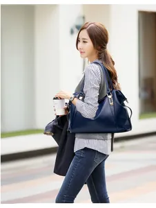 Navy blue leather tote bag with gold hardware shown in a stylish urban street setting