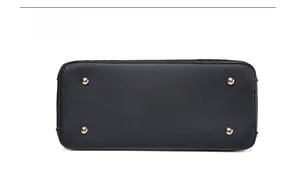 Detailed base of black litchi pattern handbag featuring four golden protective metal feet