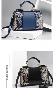 Detailed macro of patent leather bags with gold floral embroidery and contrast edge paint