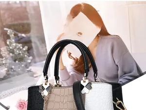Macro view of crocodile embossed leather handbag with tri-color stitch and clover charm