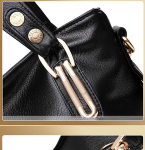 Detail of black lychee grain leather with pale gold U-shaped metal ring and engraved rivets