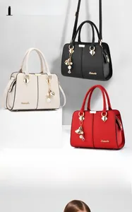 Close-up of litchi grain leather handbags in black, off-white, and red with pearl charms