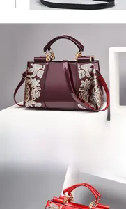 Close-up of glossy patent leather handbags with sequin floral patterns and gold hardware