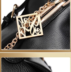 Detail of black lychee grain leather handbag with hollowed golden metal pendant