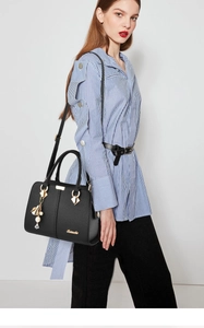 Close-up of black lychee grain leather handbag with gold logo and elegant tassel charm