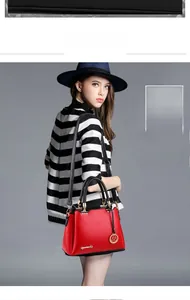 Detail of red bucket bag featuring black handles, gold hardware, and metal logo