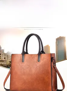 Detail shot of brown lychee grain faux leather tote bag with dark handles and black hardware