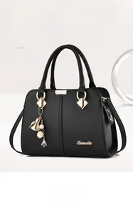 Detail of black lychee grain faux leather handbag with gold pearl charm and brand logo
