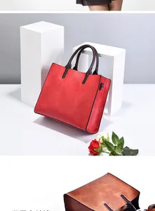 Detail of red leather tote bag showing side metal D-ring buckle and handle attachment