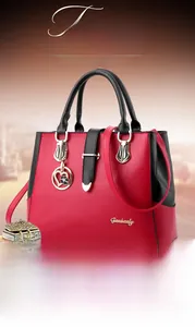 Close-up of red and black PU leather handbag with gold metal ring and thin shoulder strap