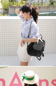 Detail of black soft leather backpack with litchi texture and gold hardware on model