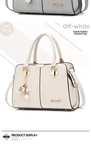 Detailed macro view of cream litchi texture handbag with gold hardware and pearl charm