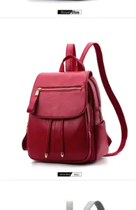 Detail view of burgundy pebble leather backpack with decorative tassels and gold zippers