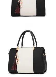 Detailed 3/4 view of a black and white women's handbag with a cat charm and tassel