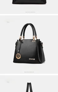 Detail of black trapezoid bucket bag with gold hardware and circular handles