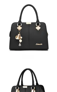 Detail of black litchi grain leather handbag with gold logo and pearl charm