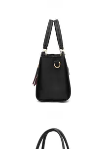 Detail of black lychee grain leather handbag featuring gold hardware and tassel charm