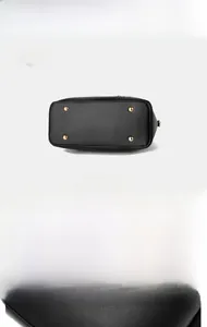 Detail view of black bucket bag bottom showing golden protective studs and leather texture