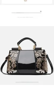 Detail of glossy black patent leather handbag with sparkling gold floral sequins and metal chain