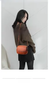 Sac bandoulière rond orange en cuir texturé porté par un mannequin en intérieur