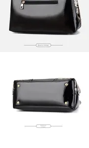 Detail of glossy black patent leather bag featuring back zipper pocket and metal bottom studs