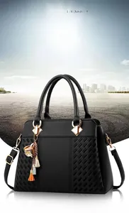 Close-up of black PU handbag featuring woven texture and gold floral tassel charms
